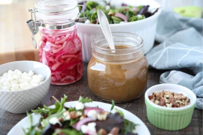 Salad ingredients: crumbled goat cheese, pickled onions, homemade balsamic dressing, candied pecans, and spring mix lettuce.