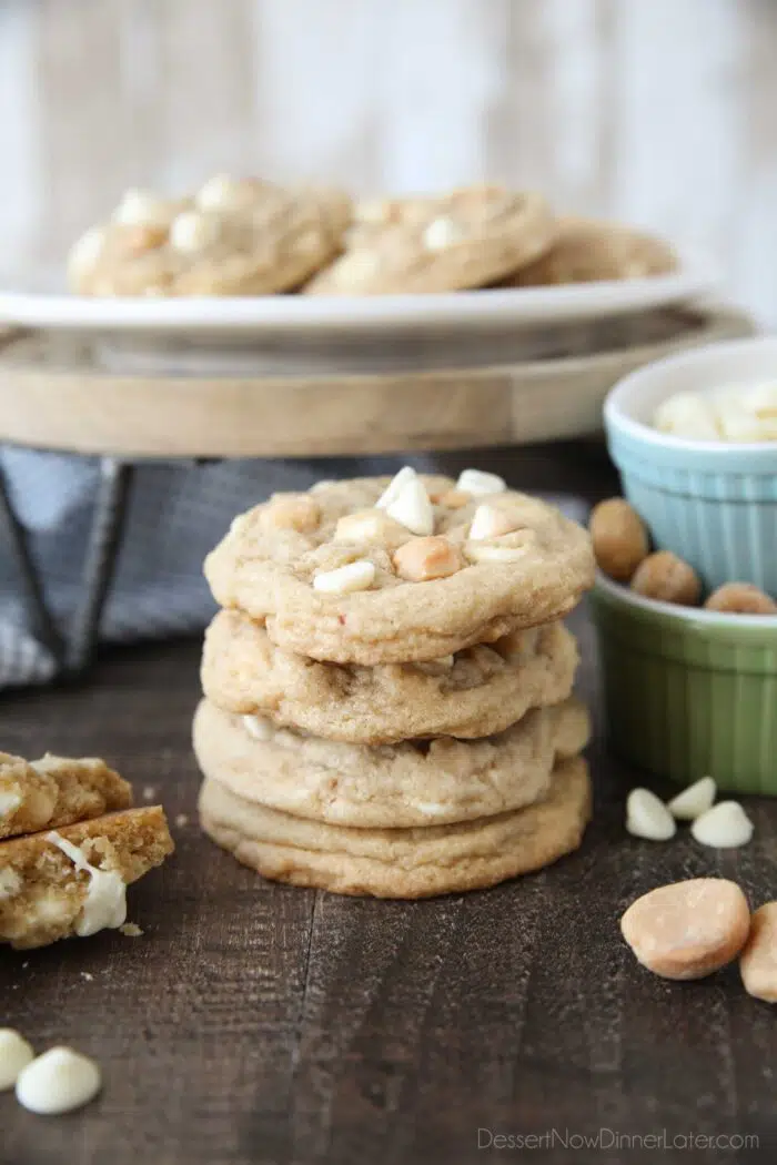 Stacked White Chocolate Macadamia Nut Cookies with extra nuts and white chocolate chips on the side.