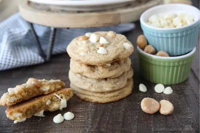 Stack of White Chocolate Macadamia Nut Cookies with one cookie broken in half to show the soft center with melted white chocolate chips.