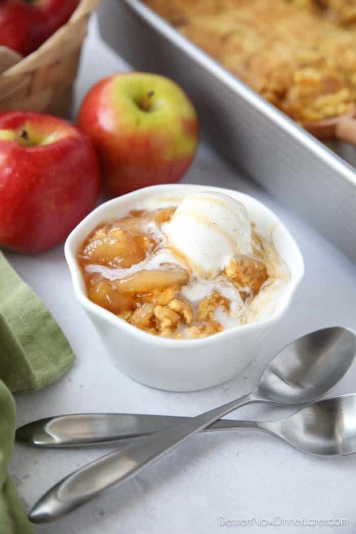 Close up of a bowl full of caramel apple dump cake and vanilla ice cream on top.