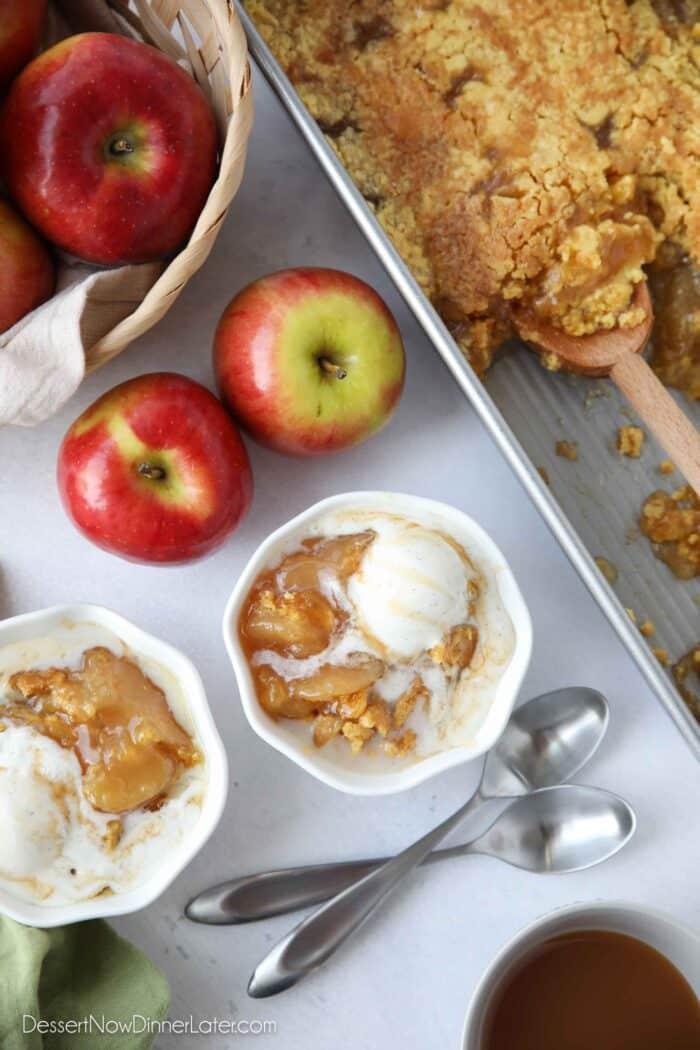 Top view of two bowls of apple cobbler with caramel sauce and ice cream melting on top.