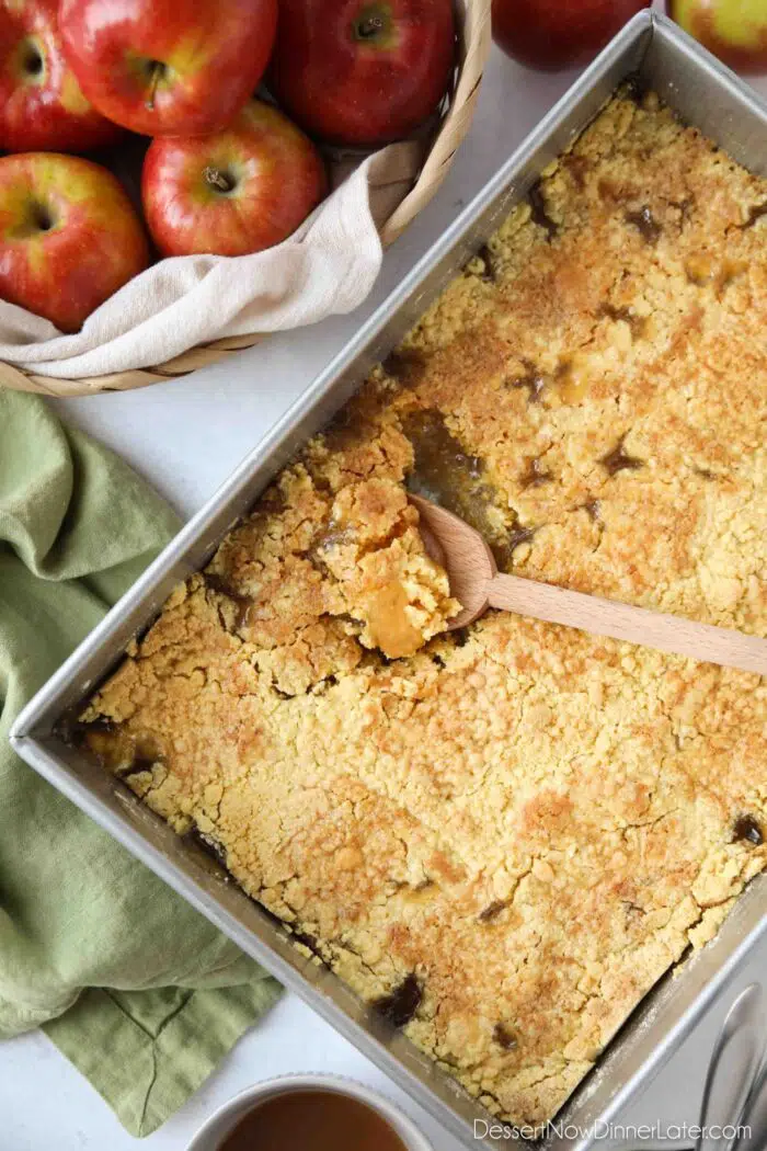 Baking pan with a spoon scooping up some caramel apple dump cake.