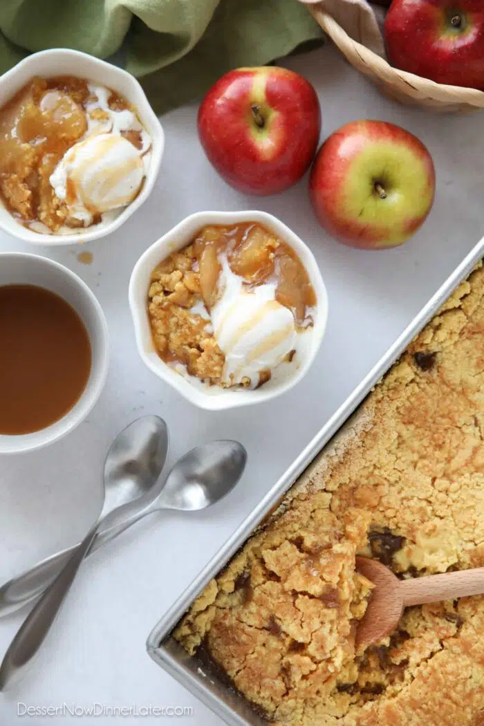 Top view of two bowls of apple cobbler with caramel sauce and ice cream melting on top.