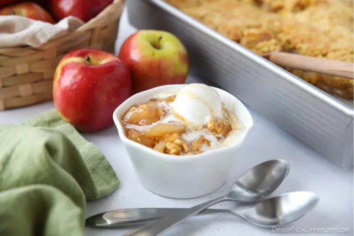 Close up side view of bowl full of caramel apple dump cake and vanilla ice cream.