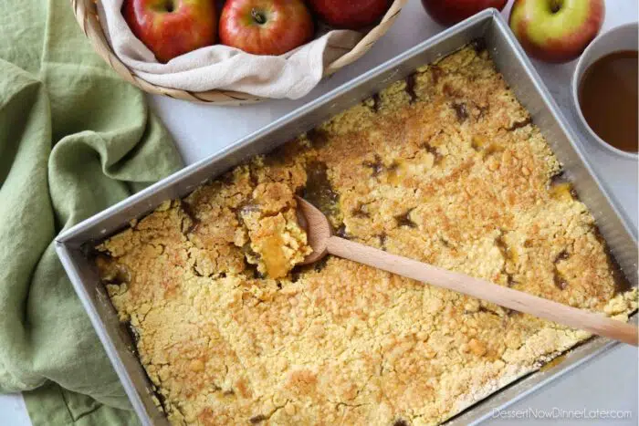 Baking pan with a spoon scooping up some caramel apple dump cake.