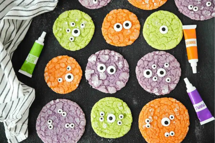 Top view of bright colored Halloween cookies with eyes on a dark surface.