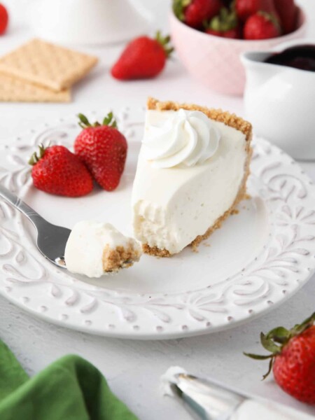 Slice of no bake cheesecake on a plate with a fork full.