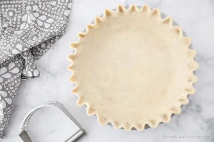 All butter pie crust in tin with crimped edges.