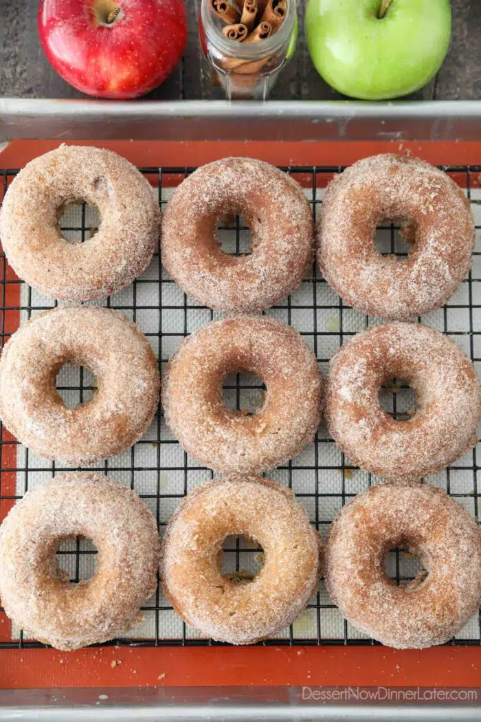 Apple cider donuts cooling on a wire rack.