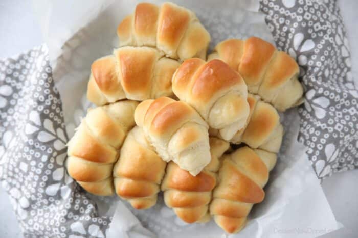 Top view of homemade crescent rolls stacked inside a bread basket.