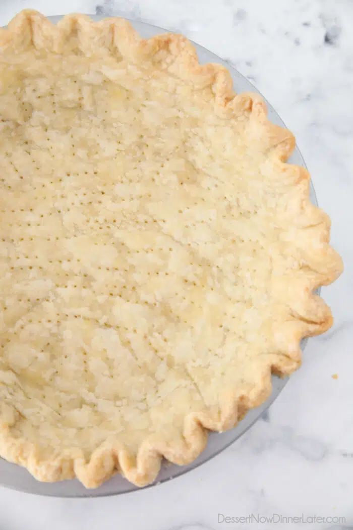 Close up of light golden brown pie crust baked in pan.