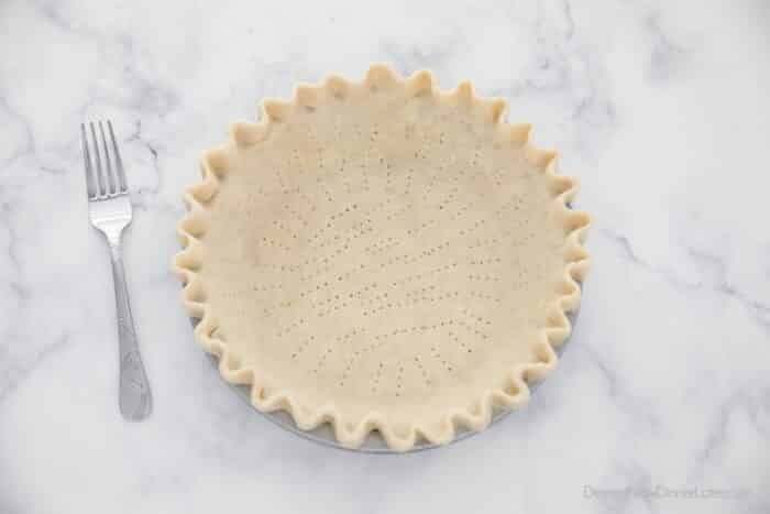 Unbaked pie crust with holes poked in the bottom and sides.