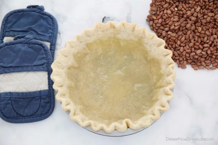 Partially baked pie crust after having removed the parchment paper with dry beans.