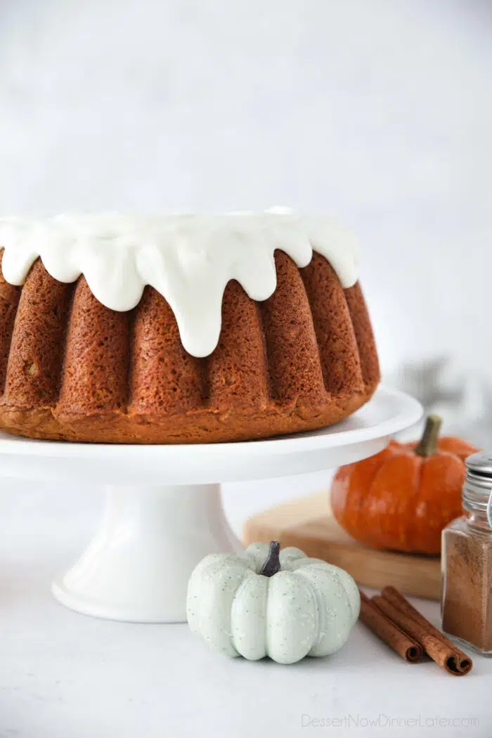 Side close up view of pumpkin bundt cake with drips of cream cheese frosting coming down the sides.