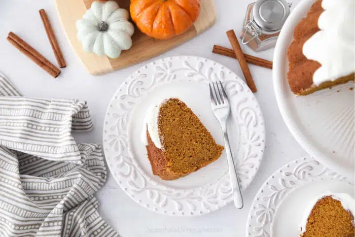 Top view of a slice of pumpkin bundt cake with cream cheese frosting on a plate with a fork.