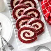 Rectangular platter with swirls of red velvet cake roll filled with cream cheese frosting.