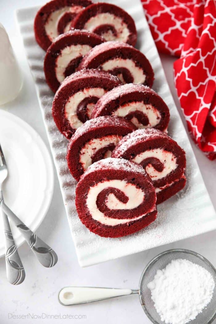 Rectangular platter with swirls of red velvet cake roll filled with cream cheese frosting.