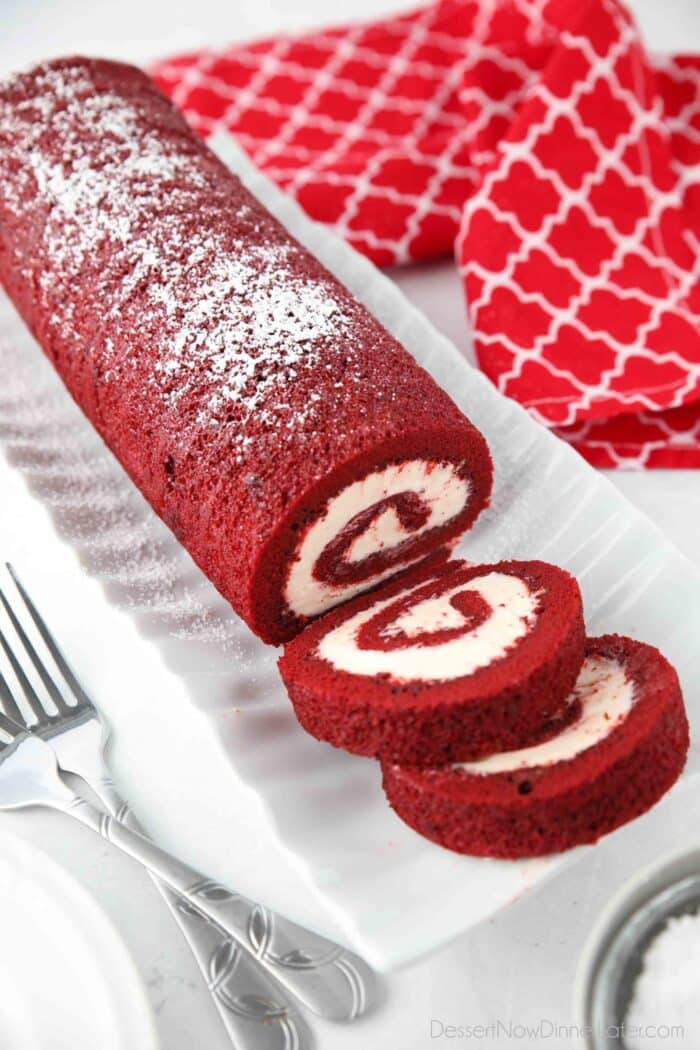 Red Velvet Cake Roll on a platter with a couple of slices cut.