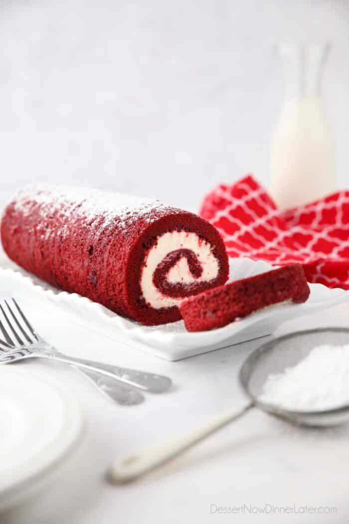 Side view of red cake and white frosting rolled up.