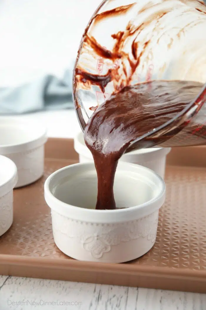 Pouring chocolate cake batter into ramekins.