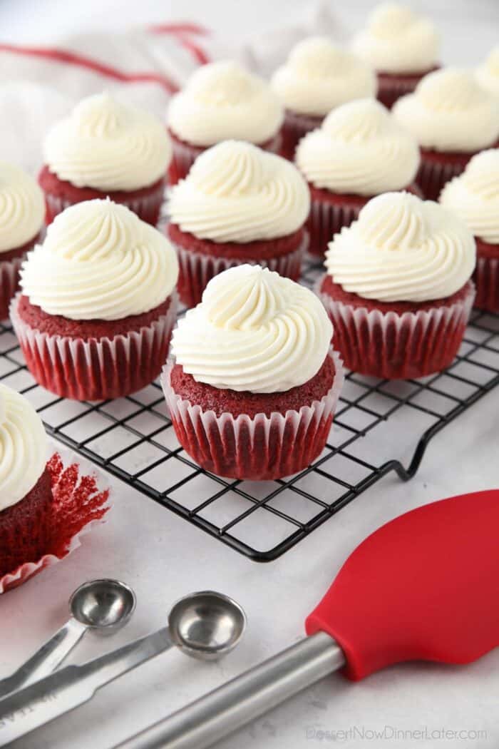 Red Velvet Cupcakes with cream cheese frosting on a cooling rack.