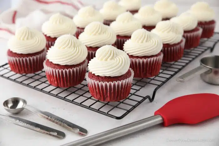 Red Velvet Cupcakes with cream cheese frosting on a wire cooling rack.