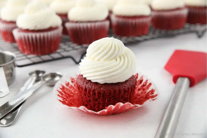 A red velvet cupcake with the wrapper pulled down to show the fluffy moist texture.