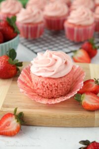 Side view of a strawberry cupcake with the wrapper pulled down to show the texture of the cake.