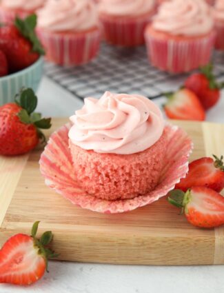 Side view of a strawberry cupcake with the wrapper pulled down to show the texture of the cake.