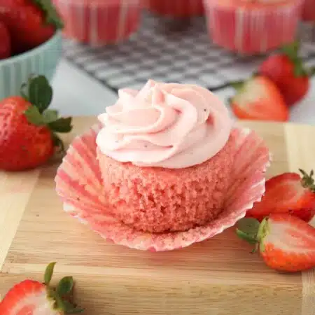 Side view of a strawberry cupcake with the wrapper pulled down to show the texture of the cake.
