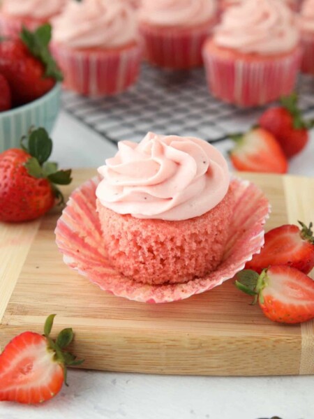 Side view of a strawberry cupcake with the wrapper pulled down to show the texture of the cake.