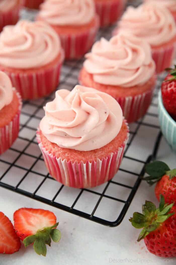 Frosted strawberry cupcakes on a wire cooling rack.