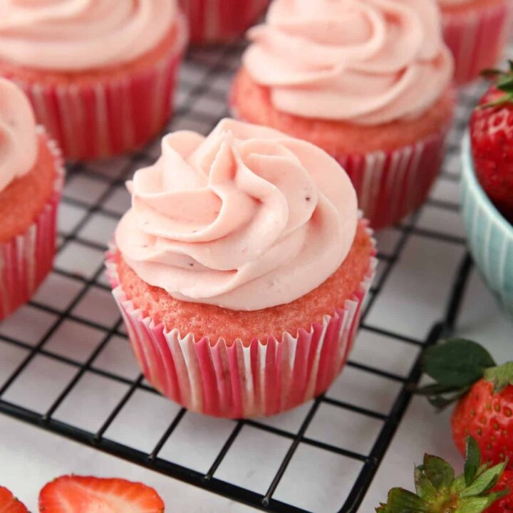 Frosted strawberry cupcakes on a wire cooling rack.