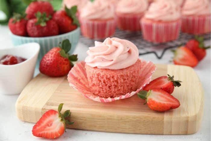 Side view of a strawberry cupcake with the wrapper pulled down to show the texture of the cake.