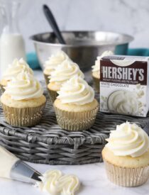 Cupcakes topped with white chocolate pudding buttercream frosting made with instant pudding mix.