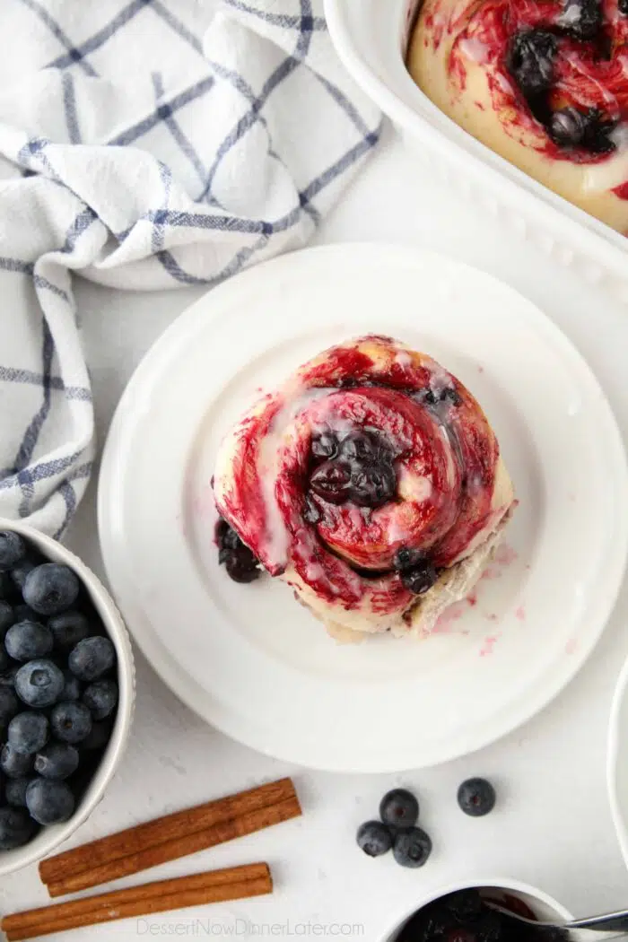 Top view of single blueberry cinnamon roll on a plate.