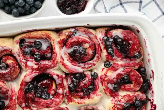 Close-up of cinnamon rolls with whole fruit blueberry sauce and a glaze.