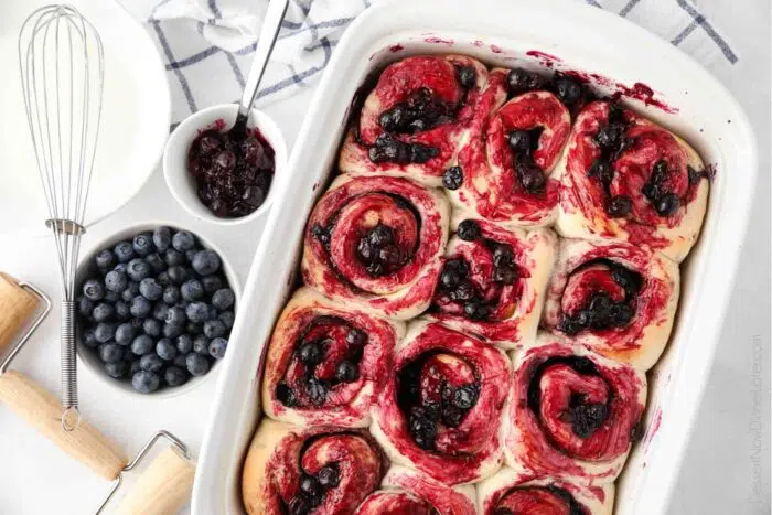 Dish of cinnamon rolls with blueberry sauce on top.