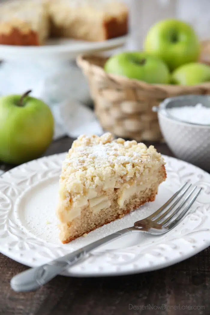 Slice of apple cake on a plate with crunchy streusel on top.