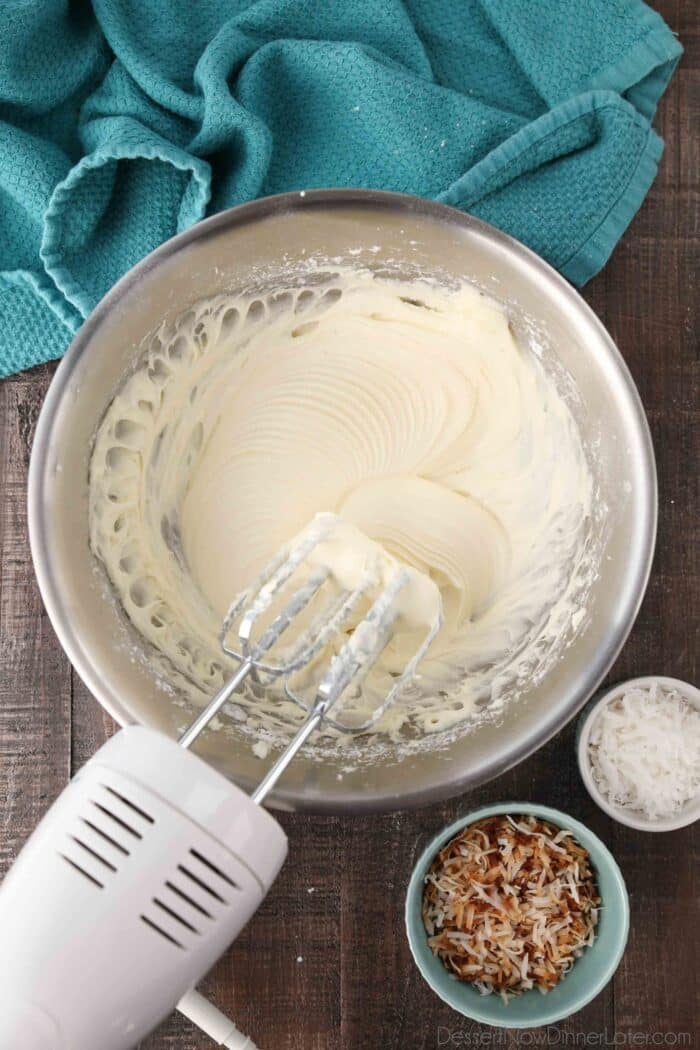 Mixing bowl and beaters filled with coconut cream cheese frosting.