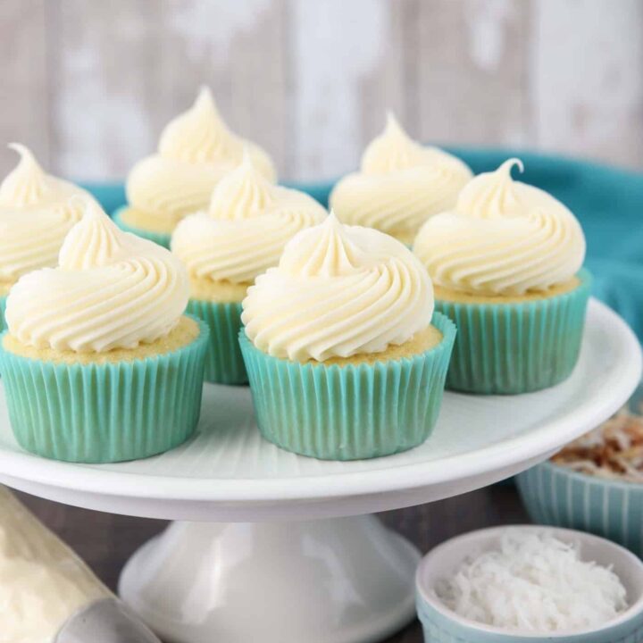 Big swirls of coconut cream cheese frosting piped onto cupcakes.