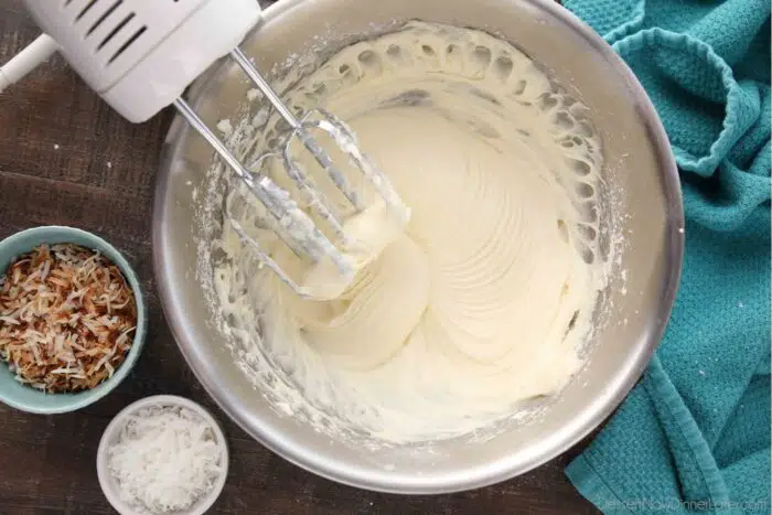 Top view of mixing bowl with beaters after mixing coconut cream cheese frosting.