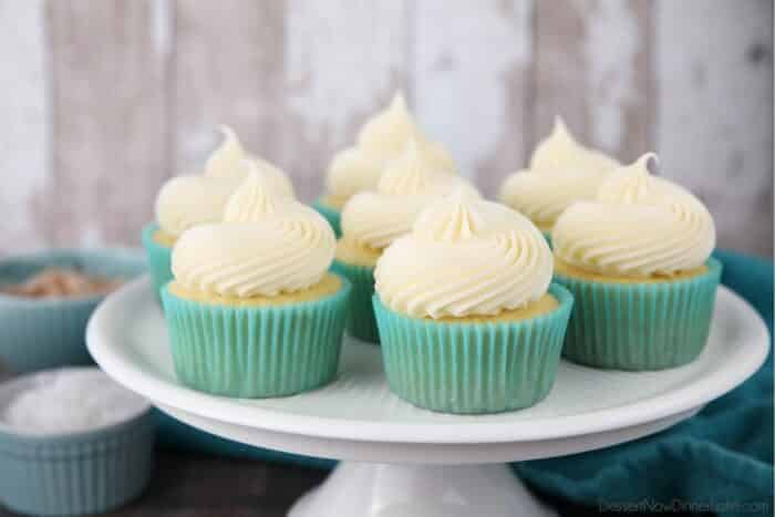 Focus on coconut cream cheese frosting piped high onto cupcakes.