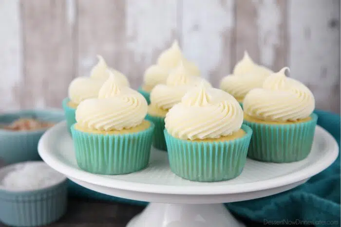 Focus on coconut cream cheese frosting piped high onto cupcakes.