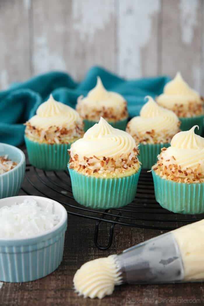 Close-up side view of coconut cupcakes with coconut cream cheese frosting and toasted coconut on top.