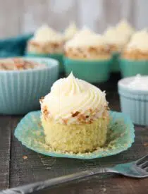 Paper wrapper pulled down exposing the crumb of a coconut cupcake.