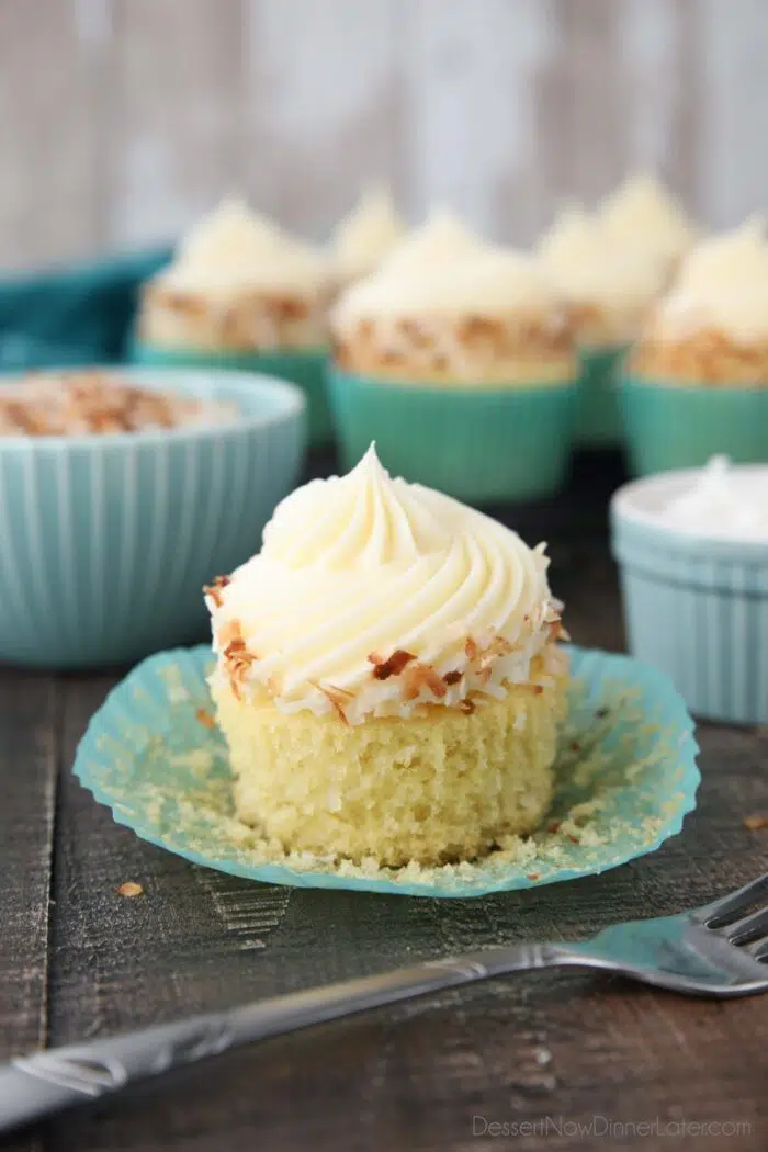 Paper wrapper pulled down exposing the crumb of a coconut cupcake.