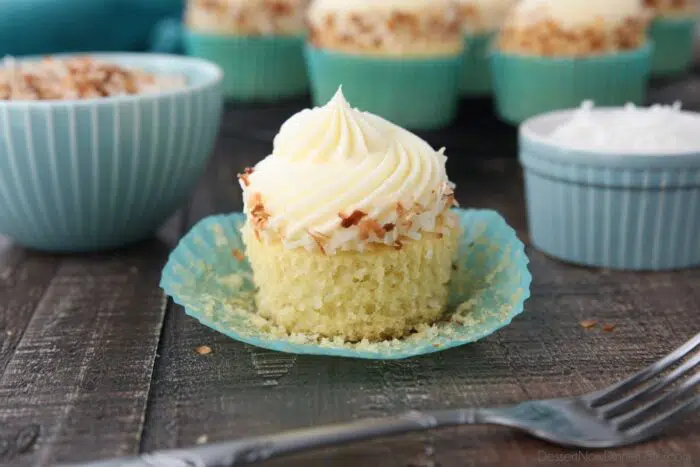 Close-up side view of a coconut cupcake with the paper wrapper pulled down.