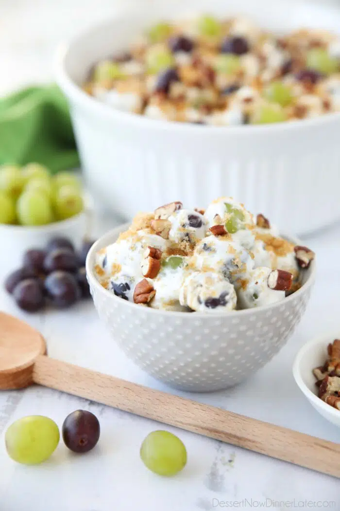 Creamy grape salad in an individual bowl topped with chopped pecans and brown sugar.