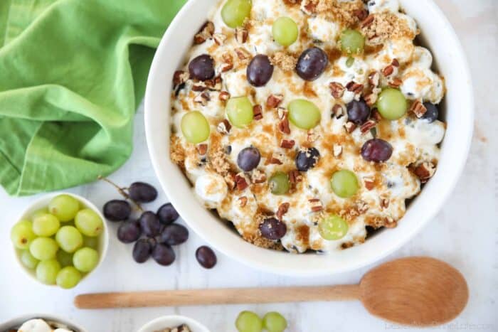 Red and green grapes in a fluffy cream cheese sauce topped with brown sugar and pecans.